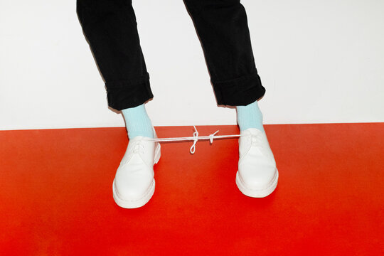Conceptual image of person wearing shoes and having a knot in the lace