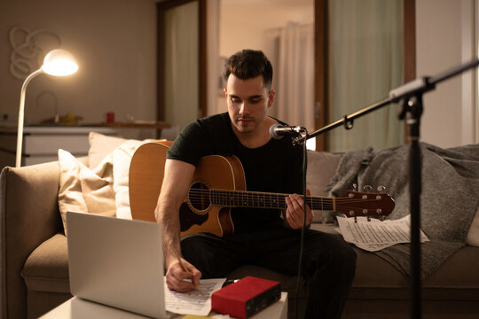 Male guitarist writing song at home