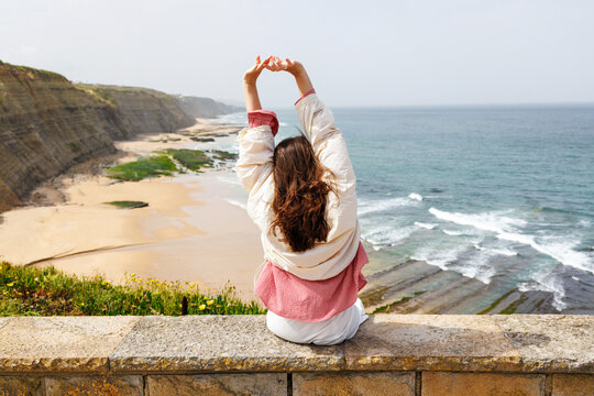 Woman enjoying travel in Portugal stretching arms on scenic coastline