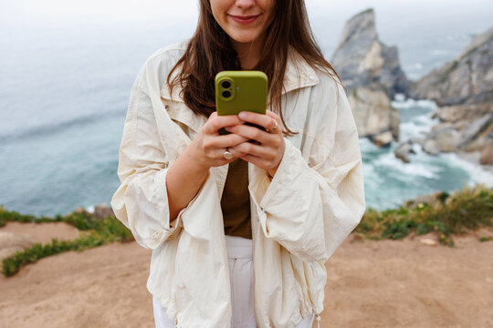 Woman traveling with smartphone by ocean cliffs