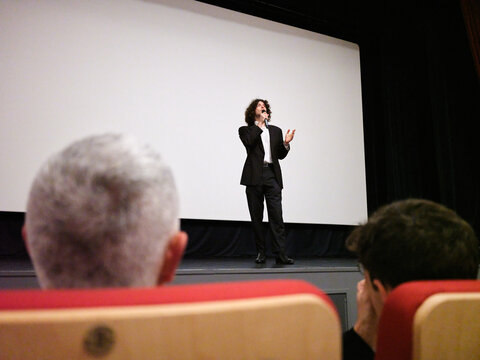 Male speaker presenting on stage during a public event