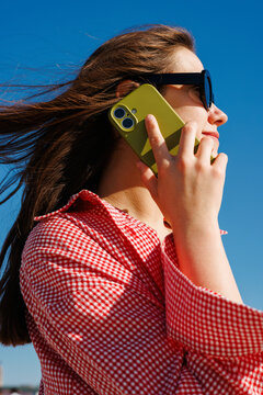 Woman holding smartphone outdoors with blue sky