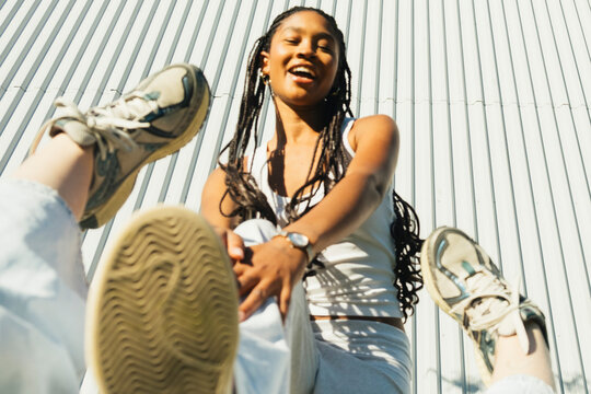 Young woman posing playfully with sneakers toward camera in urban sett