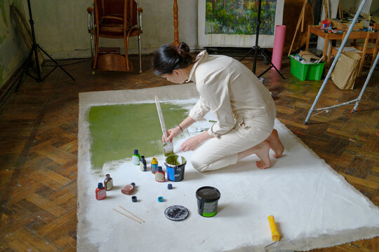artist painting a white canvas green 