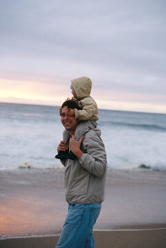 Man carrying child on shoulders at beach film photo