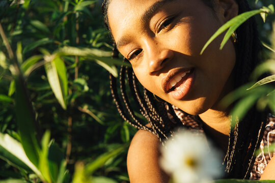 Young woman surrounded by greenery in warm evening light