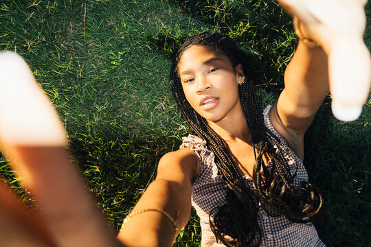 Young woman posing on grass with hands framing face in flash portrait