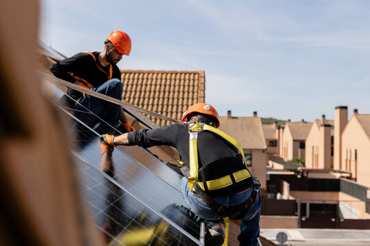 Workers installing solar panels generating clean energy on roof