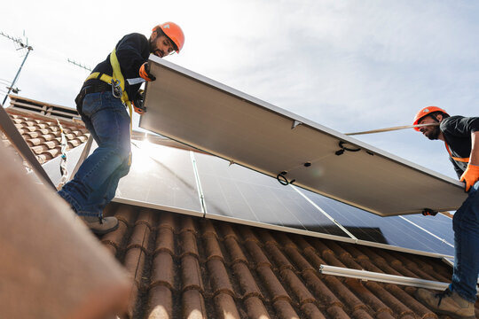 Workers installing solar panel on a tiled roof