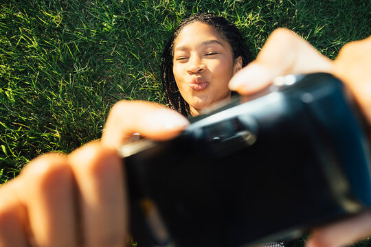Young woman holding camera above face in playful flash portrait