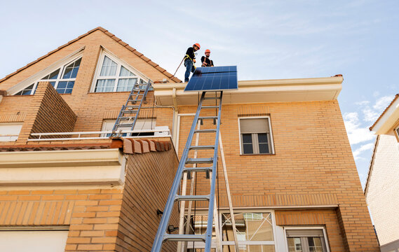 Installers workers installing solar panel on house roof