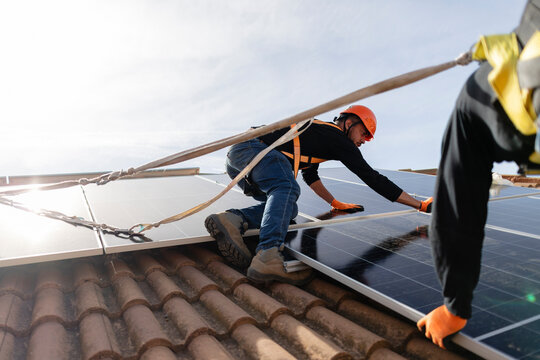 Workers installing solar panels on a building rooftop