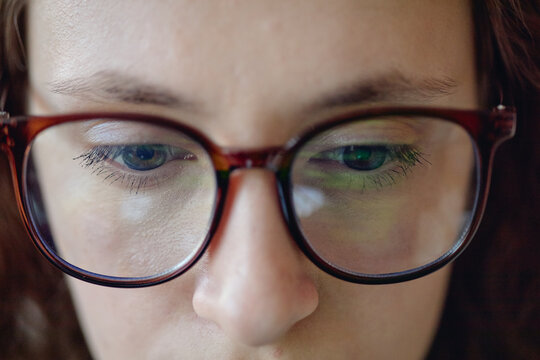 Close up of Caucasian woman wearing eyeglasses, focusing on screen with concentrated gaze. Ideal for office work marketing