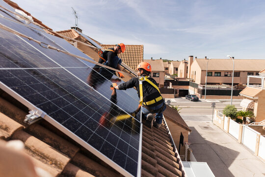 Solar panel installers installing renewable energy system on rooftop