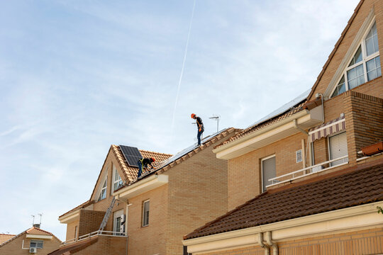 Workers installing solar panels on residential roof