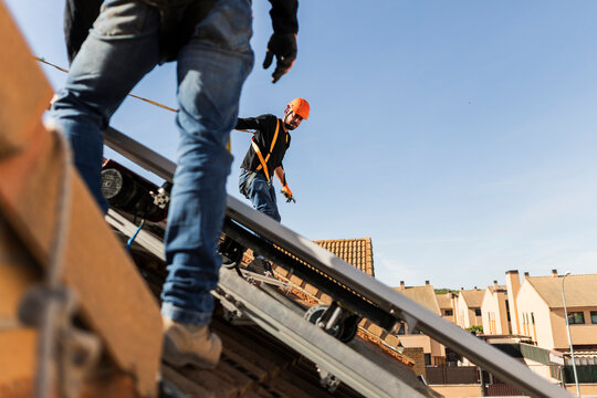 Workers installing solar panels on residential roof
