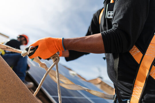 Worker installing solar panels on rooftop focusing on safety
