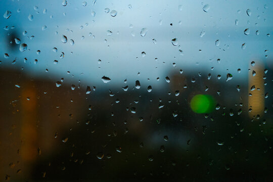 Rainwater Drops on a Window During Evening Hours in a City