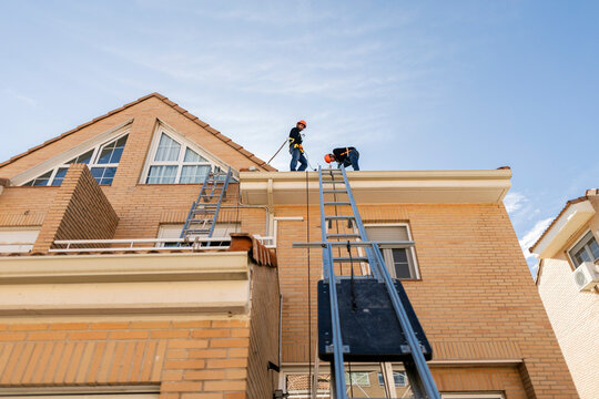Workers installing and repairing building roof gutters