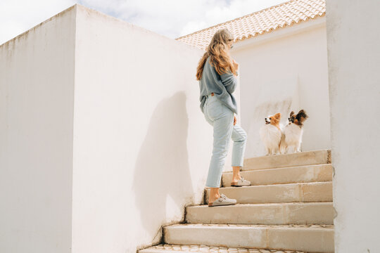 Woman Walking Up Outdoor Stairs with Two Small Papillon Dogs