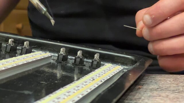 Hands craft LED lights with care as tools glide over small components. Step into a warm workshop filled with creativity and expertise in every movement.