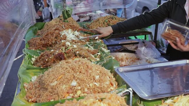 Street Food Vendor Packaging Stir Fry Rice Pad Thai Noodles, Pad Mee Korat (Northeast Thailand Style Stir Fried Noodles) in Plastic Container For Takeout at Bangkok Open Night Market