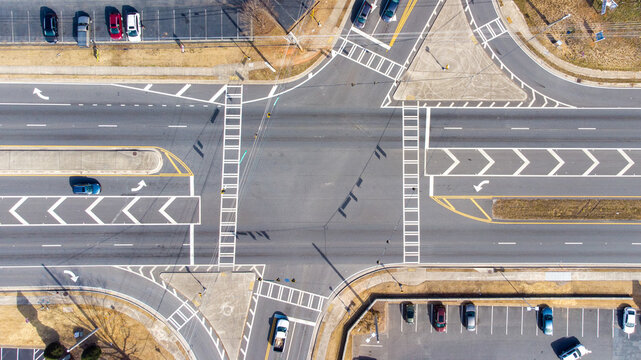 Aerial view of a road intersection with lane markings, turn arrows, and parked cars in Buford, Georgia, United States.