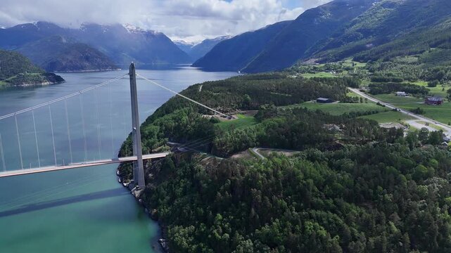 Aerial drone flyover of Hardangerbrua suspension bridge between mountain cliffs over a river, Norway