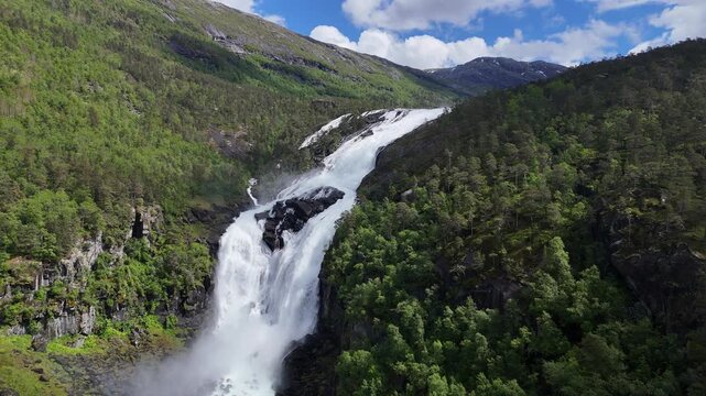 Aerial drone right to left of Nyastolfossen valley surrounded by forest, Norway