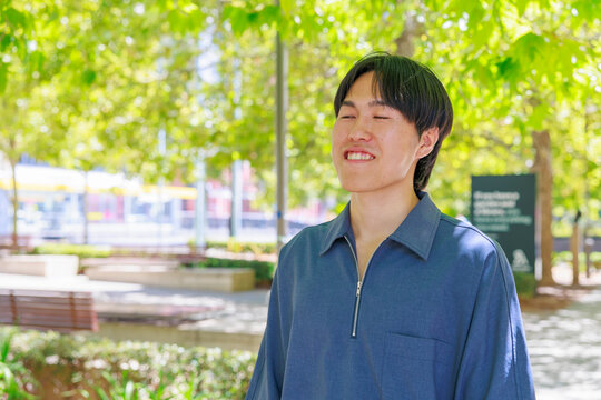 Smiling Young Japanese Man Looking at Camera in Park
