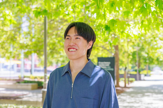 Smiling Young Japanese Man Looking at Camera in Park