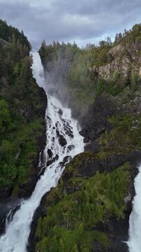 Aerial portrait drone reverse flyover of Latefossen with highway, Norway