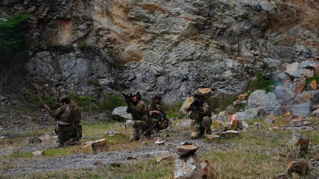 A group of soldiers in military uniforms were seen holding BB guns, cleaning their weapons and resting during a patrol while exercising their military training, playing games