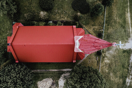 Aerial view of Rucava evangelical lutheran church with its red roof set amidst green trees and surrounding landscape in Rucavas pagasts, Dienvidkurzemes novad, Latvia.