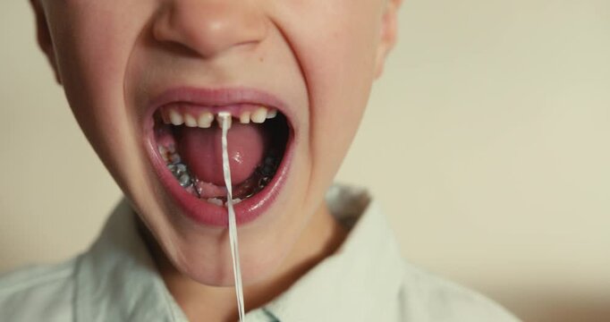 Brave young boy pulling out a loose milk tooth