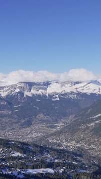 Aerial panoramic footage showcasing the snow-capped Alps mountains, forested slopes, and scattered alpine villages in the Sallanches Passy valley near Mont Blanc, Mont Joly, and Megeve, France. The