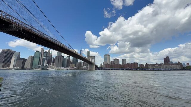 Panoramic, scenic view of Lower Manhattan skyline and Brooklyn Bridge. Motion of cars traffic on FDR drive. Financial district. Motion of East River waves. New York City, United States