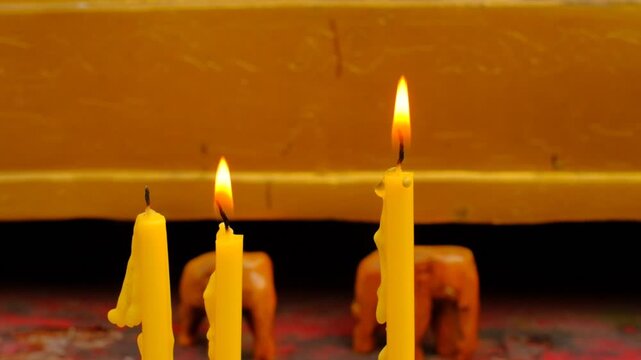Candles flicker gently near decorative elephants