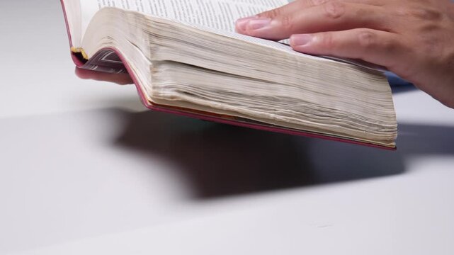 Person holding an open vintage book with many aged pages. Reading and studying for knowledge. Education. Research. Personal development. Culture. And wisdom