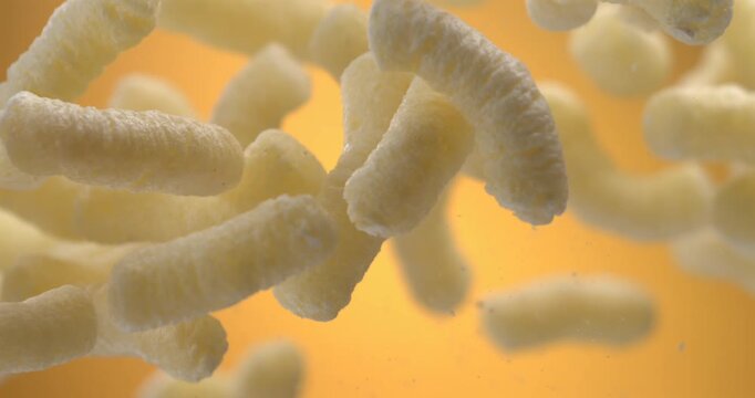 Corn sticks cheese puffs floating in the air slow motion