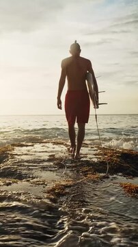 Surfer walks along a rocky coastline at sunset, carrying a surfboard after an exhilarating session. Warm golden light reflects off the wet rocks and ocean, creating a dramatic and breathtaking scene