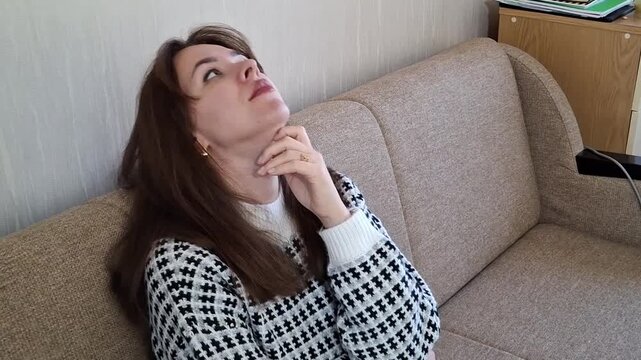 Woman sitting on a sofa with hand on face showing frustration in a living room
