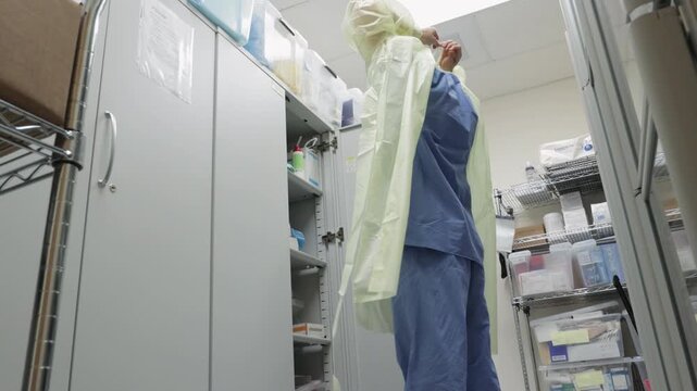  Male nurse doctor puts on personal protective equipment PPE N95 mask, face shield, glove, gown suit in hospital clinic. Medical personnel hygiene safety protection during outbreak pandemic
