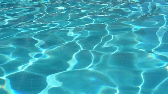 Shining azure swimming pool water with sunbeams creating rippled light patterns and abstract background texture