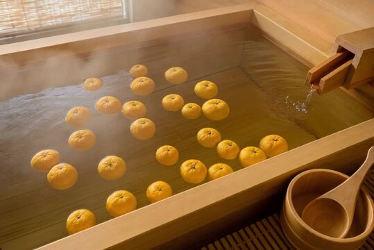Japanese yuzu citrus bath with fruits gently bobbing on steaming water in hinoki wooden tub