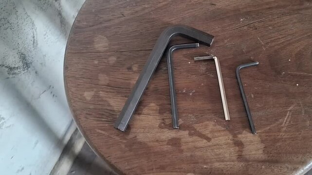 Four metal allen keys resting on a rustic wooden stool video