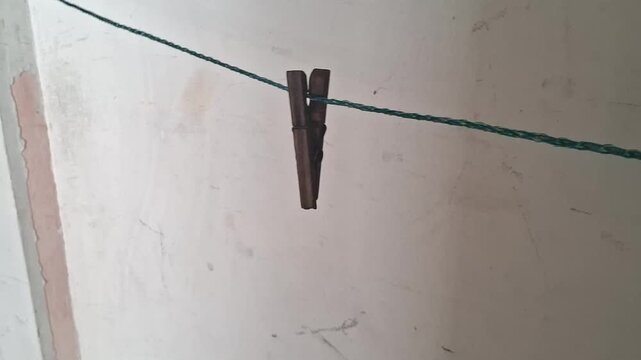 Wooden clothespin hanging on a thin string in motion video footage