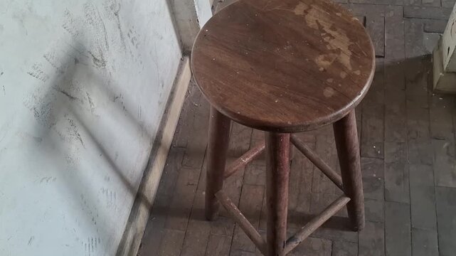 Rustic wooden stool standing on tiled floor in motion video clip