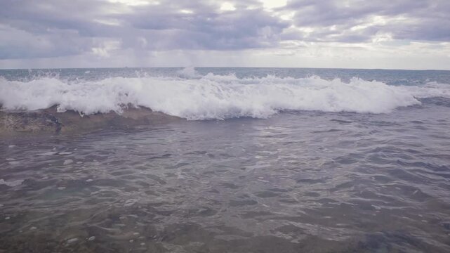 Small wave overflow crashing into beach ocean tidepool sea shore, cloudy sunset nature beauty island background. North Shore, Hawaii.