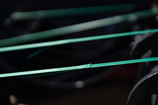 bright green polypropylene packaging straps tensioned over industrial equipment with selective focus on a frayed point
